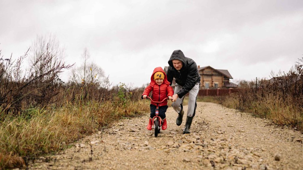 father teaching son to ride a bike